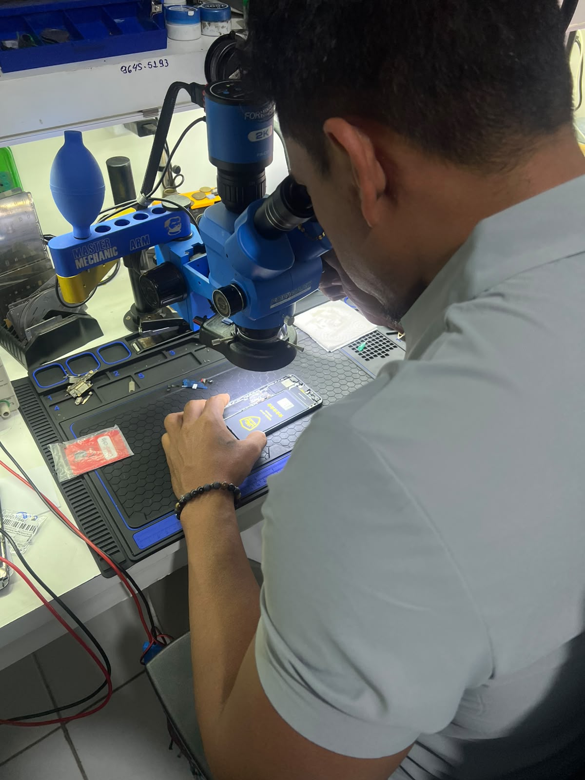 Técnico da Marcos Cell consertando um smartphone com microscópio
